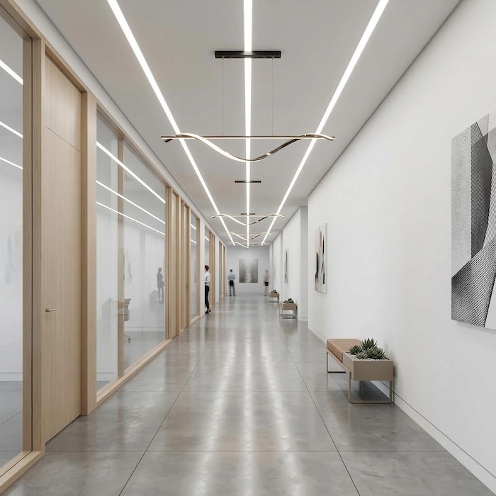 Leading-line linear lighting in a modern office hallway.