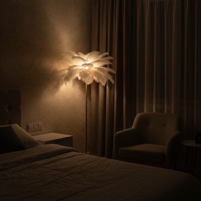 Soft shadows and warm light from a floor lamp in a bedroom corner.