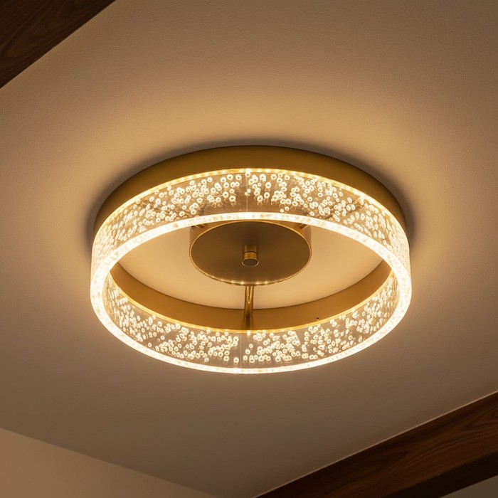 A low-angle view of a round ceiling light contrasting with a dark architectural beam.