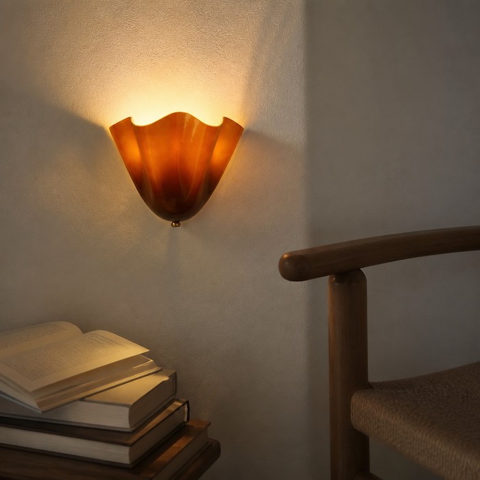 Intimate reading corner lit by a floral glass wall sconce.