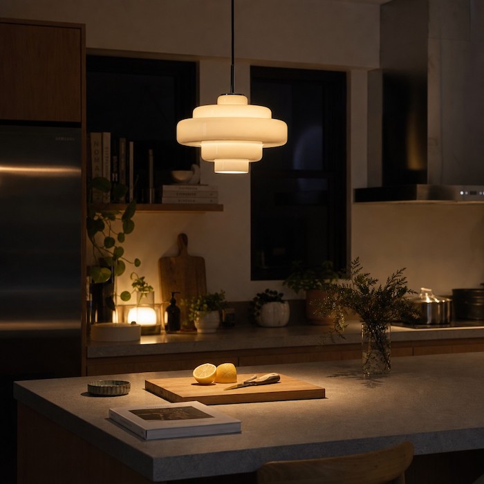 A tiered glass pendant providing both focused task lighting and soft ambient light in a room.