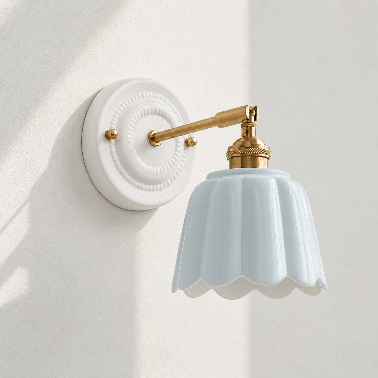 Editorial close view of pale blue ceramic petal shade and brass arm