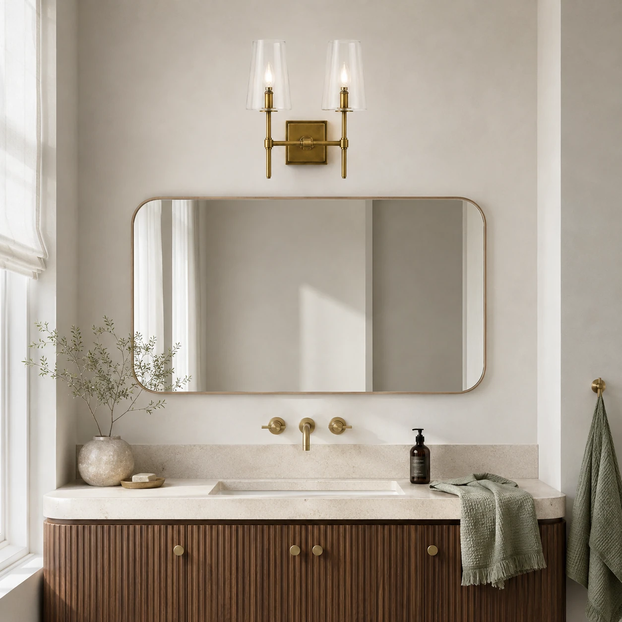 Two-head brass Yve wall sconce above a modern vanity