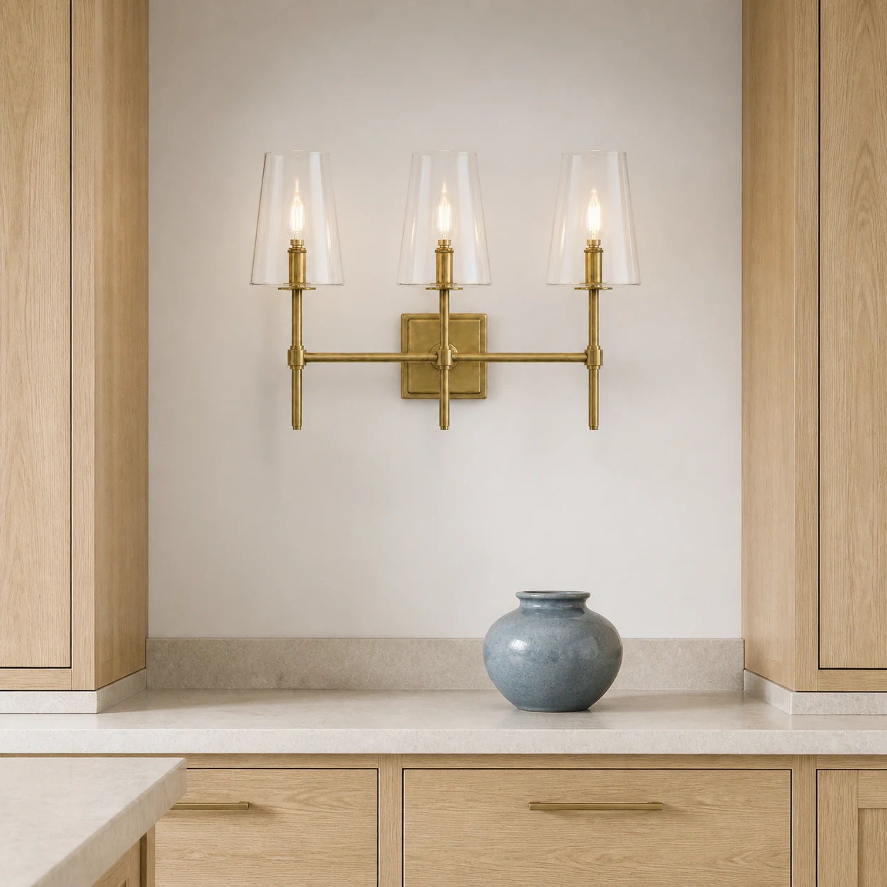 Three-head brass Yve wall sconce in a kitchen display wall