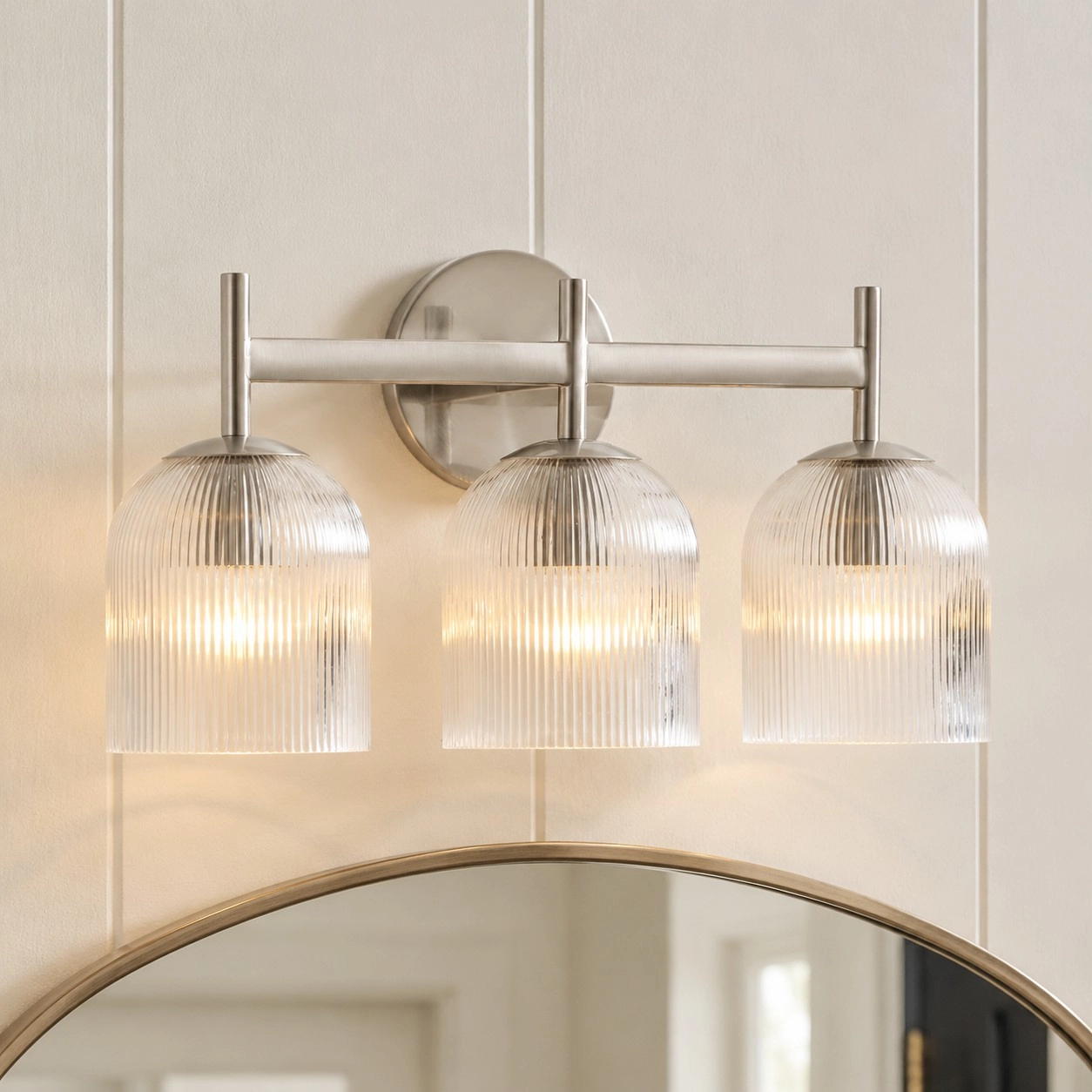 Three-head ribbed glass wall light above a mirror