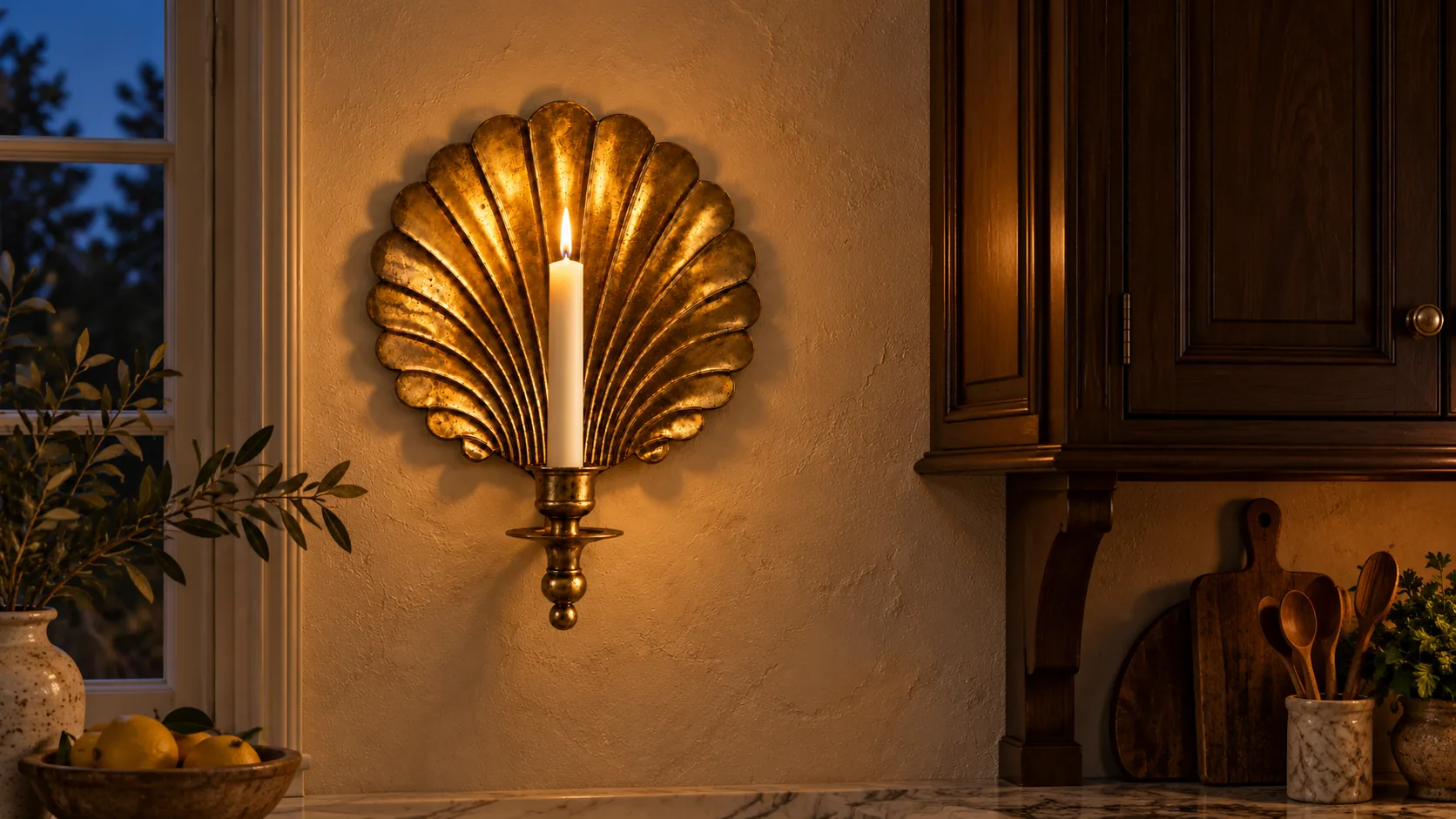 Lit brass shell candle sconce beside a kitchen cabinet